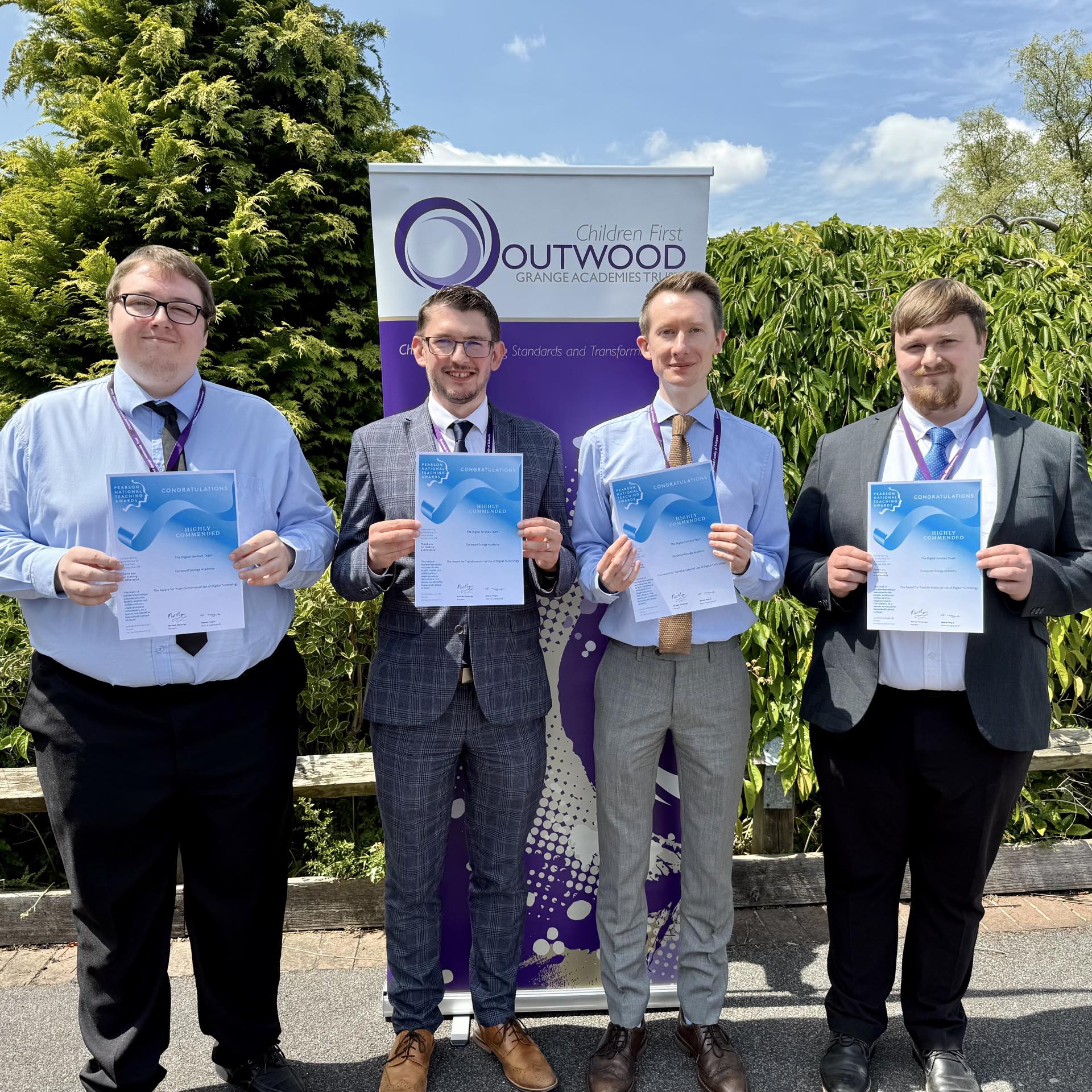 Four people are standing and holding certificates.